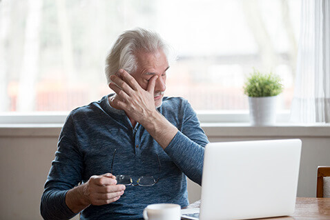 Older man at laptop with dry eye